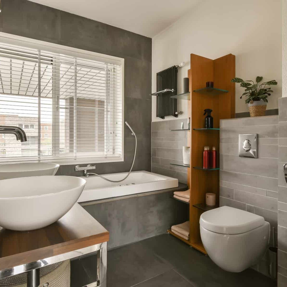 a bathroom with a sink, toilet and window in the back wall is made of dark grey tiles on the floor