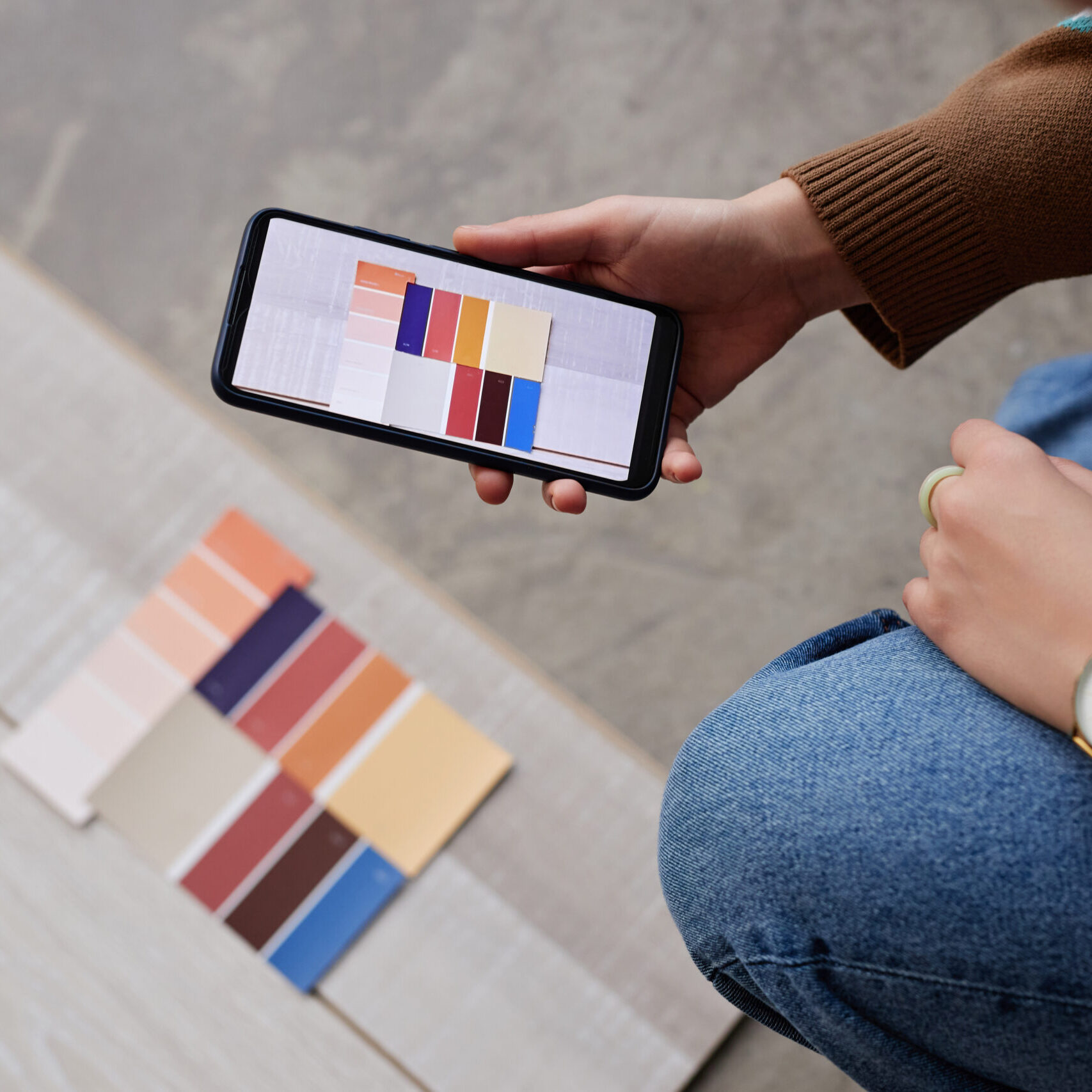 High angle view of designer choosing color for flooring and making photo on her smartphone